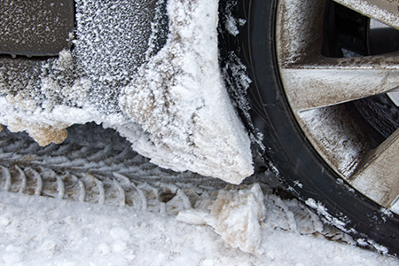 close up of a snowy tire and car side panel