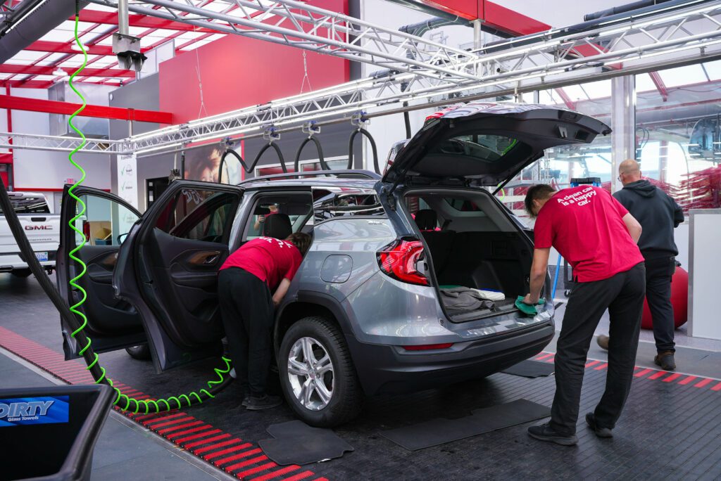 Photo of employees cleaning grey SUV at Quality Car Wash interior cleaning tunnel.